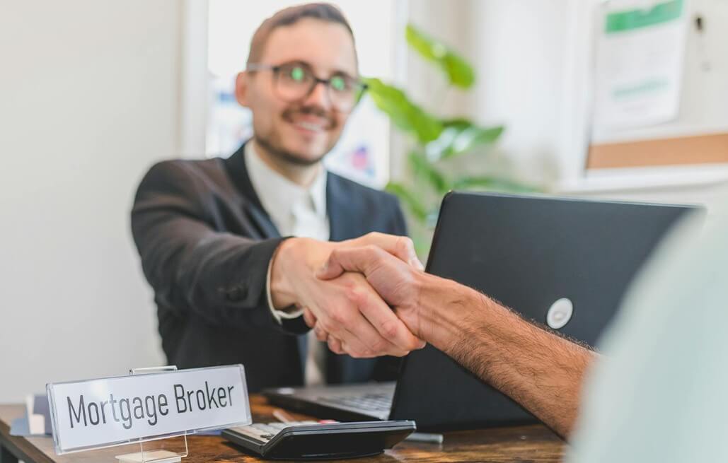 A client and a mortgage broker shake hands following a successful transaction